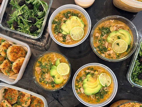 Avocado fans and a lime wheel float on shredded chicken salsa verde soup across four round bowls.