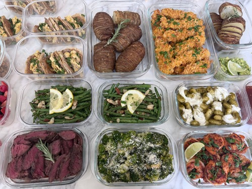 Prepared meals, salads and vegetable sides arranged in glass containers.