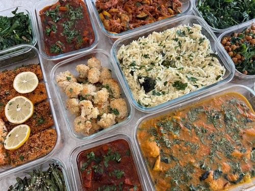 Turmeric turns the chicken veggie stew deep gold, cilantro across the surface, charred corn quinoa to the right.