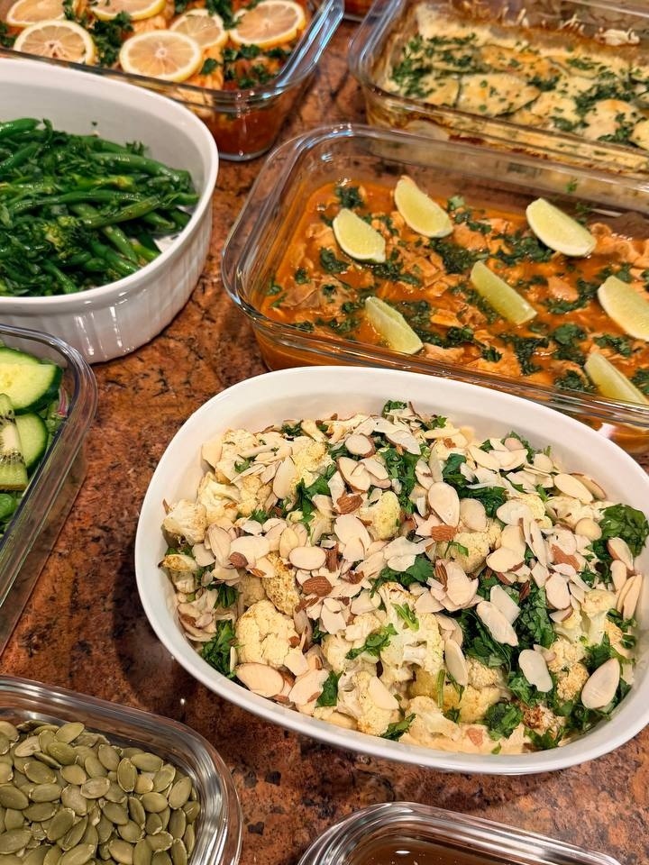 A collection of gourmet glass dishes featuring harissa baked cod with citrus, Mediterranean spiced cauliflower with toasted almonds, and a bubbly potato zucchini gratin.