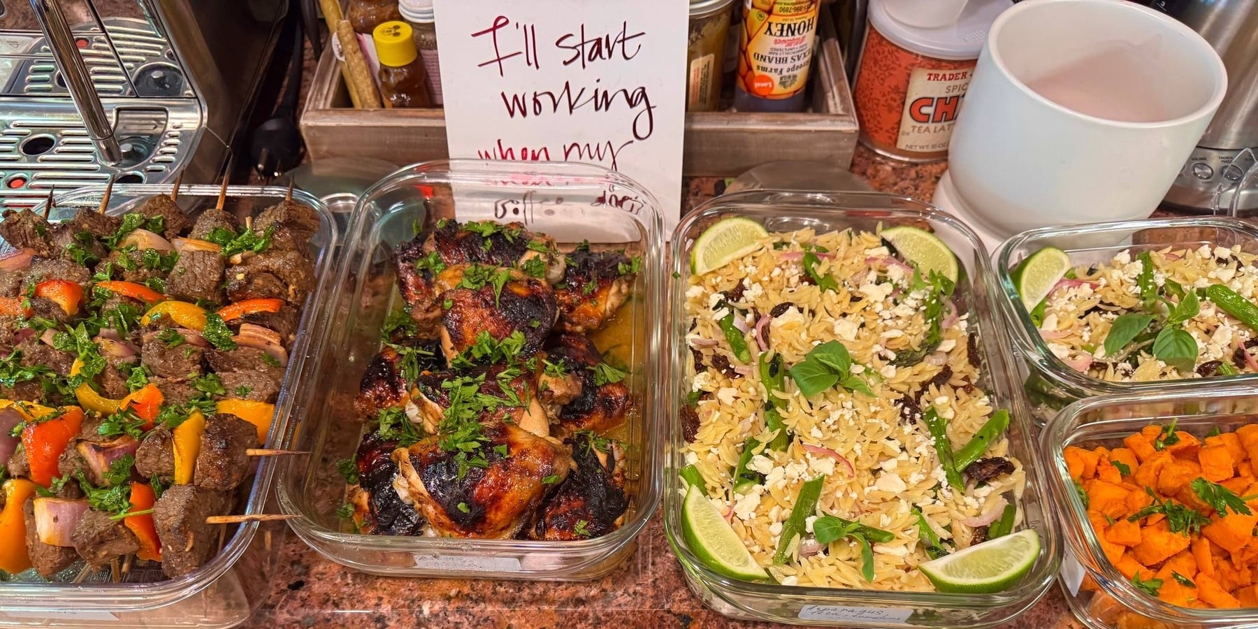 Glass containers holding beef skewers with peppers, balsamic glazed chicken thighs, and orzo salad with asparagus, sun-dried tomatoes, feta, and lime slices.