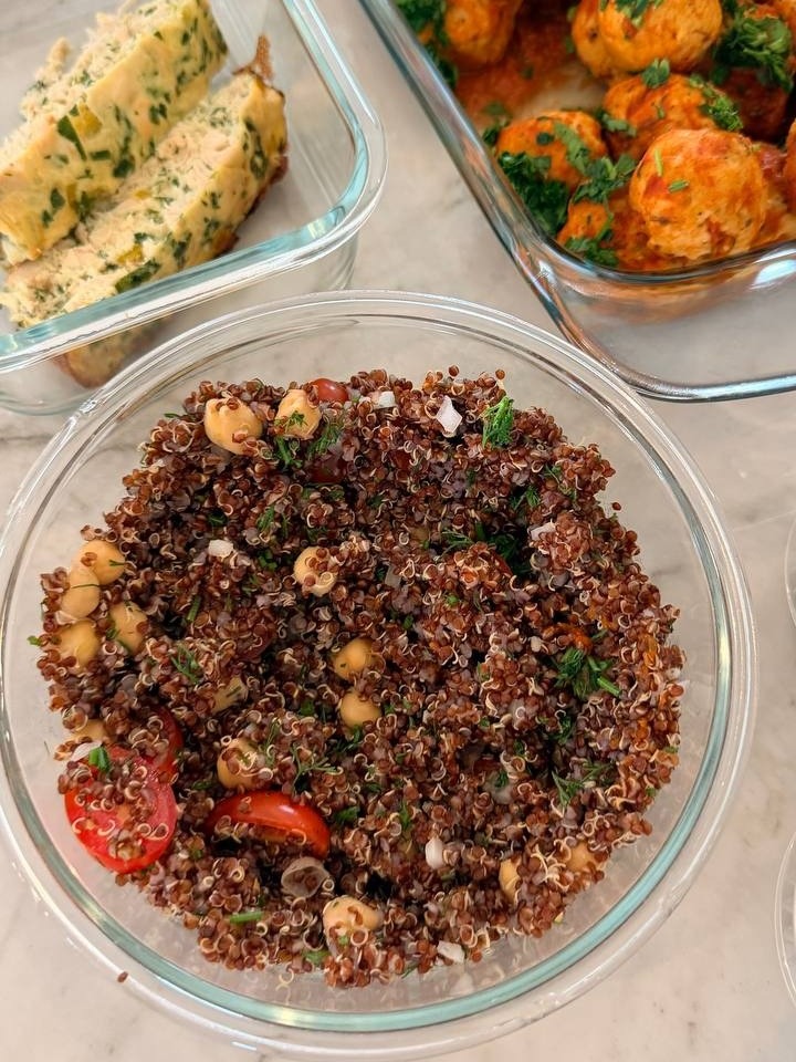 Glass containers featuring Tuscan turkey meatballs, a red quinoa salad with chickpeas and cherry tomatoes, and sliced buffalo chicken egg bake.