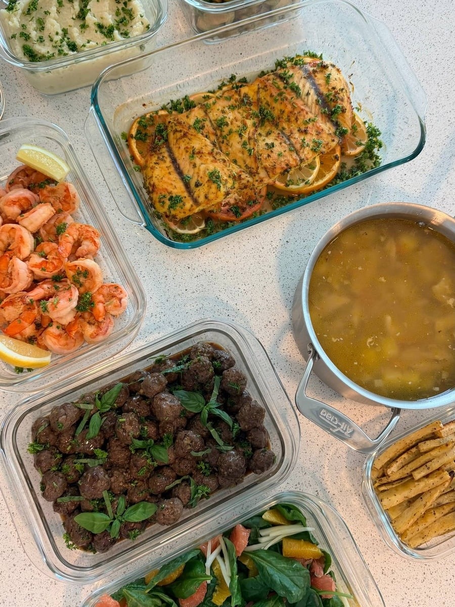 Barramundi fillets rest on orange wheels between elk meatballs, shrimp and a spinach grapefruit salad.