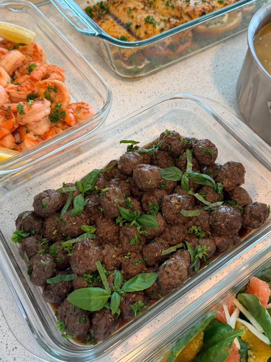 Basil leaves and parsley cover ground elk meatballs glazed dark in honey garlic sauce.