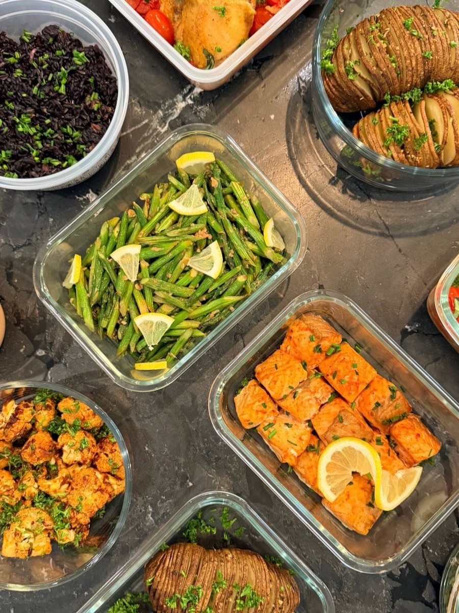 Asparagus tips and cut stalks glisten with garlic, lemon wedges tucked between them in a square dish.