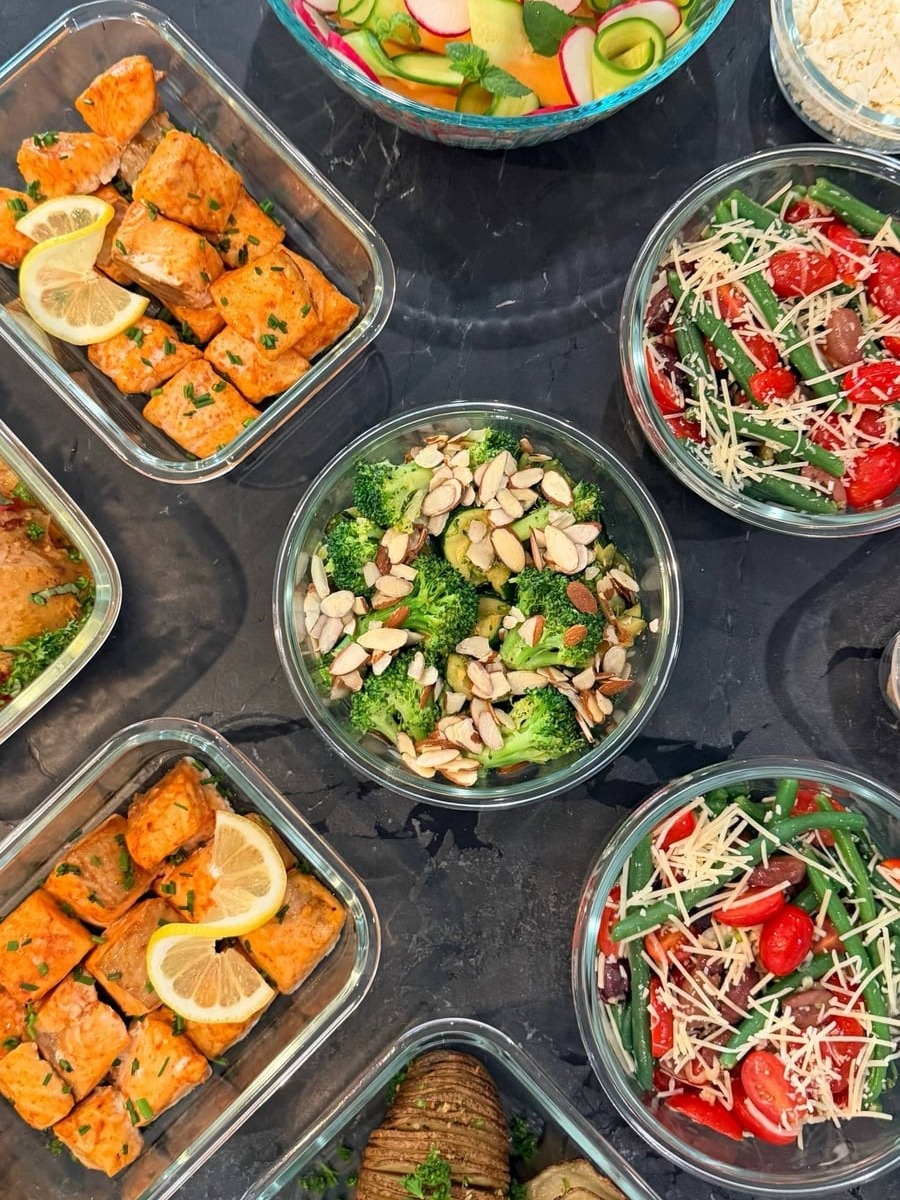 Chili almonds pile over broccoli, with green beans, cherry tomatoes, olives and shaved Asiago in the bowls around.