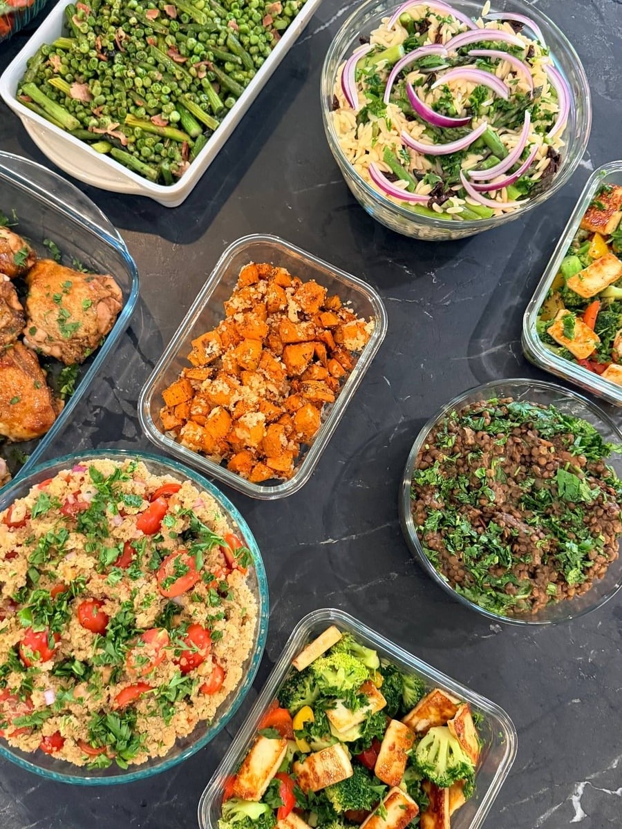 A variety of gourmet sides including seared asparagus with peas, brown rice orzo, quinoa salad, herbed sweet potatoes, and sauteed broccoli with paneer.