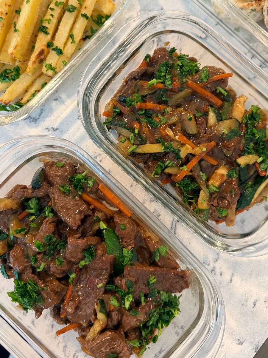 Carrot matchsticks and zucchini thread through the glossy bison stir fry, potato fries filling the tray at left.