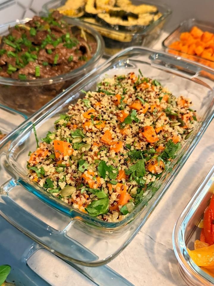 A glass container features roasted sweet potato and cilantro quinoa, alongside containers of beef stir fry, parmesan acorn squash, and roasted fajita vegetables.
