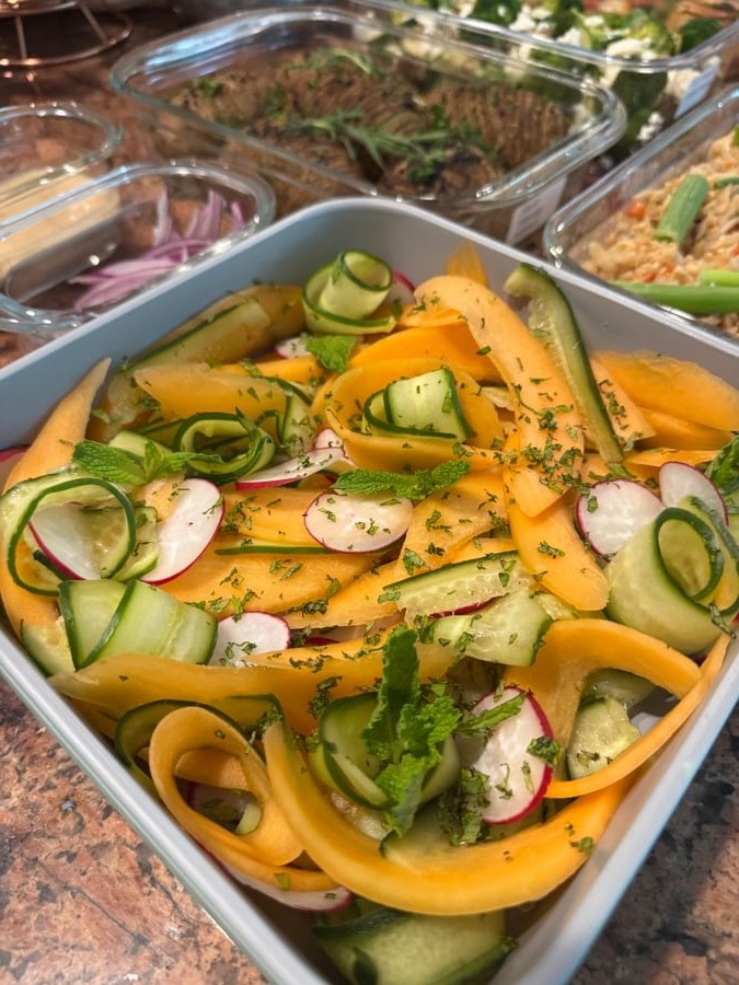 A square dish features a refreshing melon cucumber radish salad with mint, arranged in glass containers, displaying vibrant colors and artistic ribboned vegetable carvings.