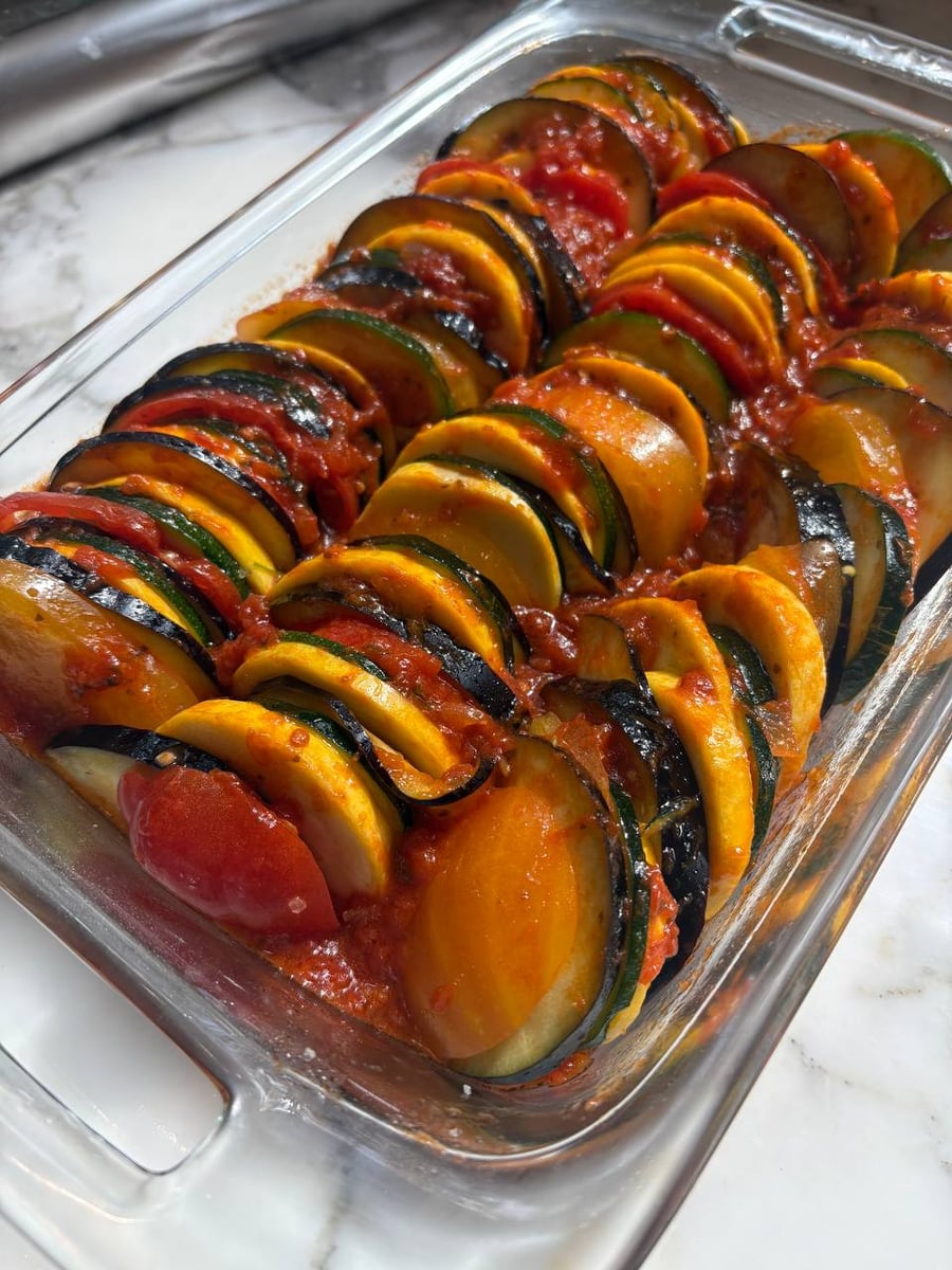 A beautifully layered ratatouille casserole with thinly sliced zucchini, squash, and eggplant, demonstrating professional plating techniques for healthy weekly dining.
