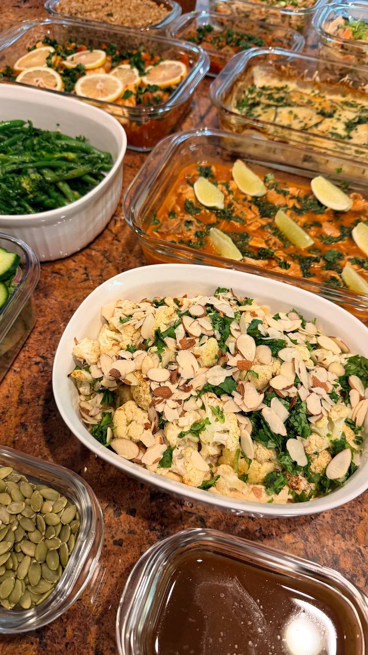 A spread of meal prep dishes including harissa cod with lime, mediterranean spiced cauliflower with almonds, and a creamy potato and zucchini gratin.