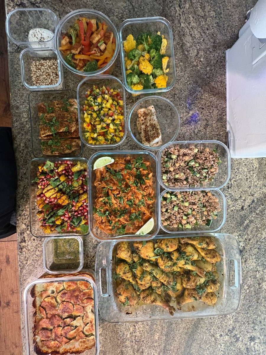 A variety of glass containers filled with zaatar chicken, blackened mahi mahi, mango salsa, herbed farro, roasted Mediterranean vegetables, and a layered potato gratin.