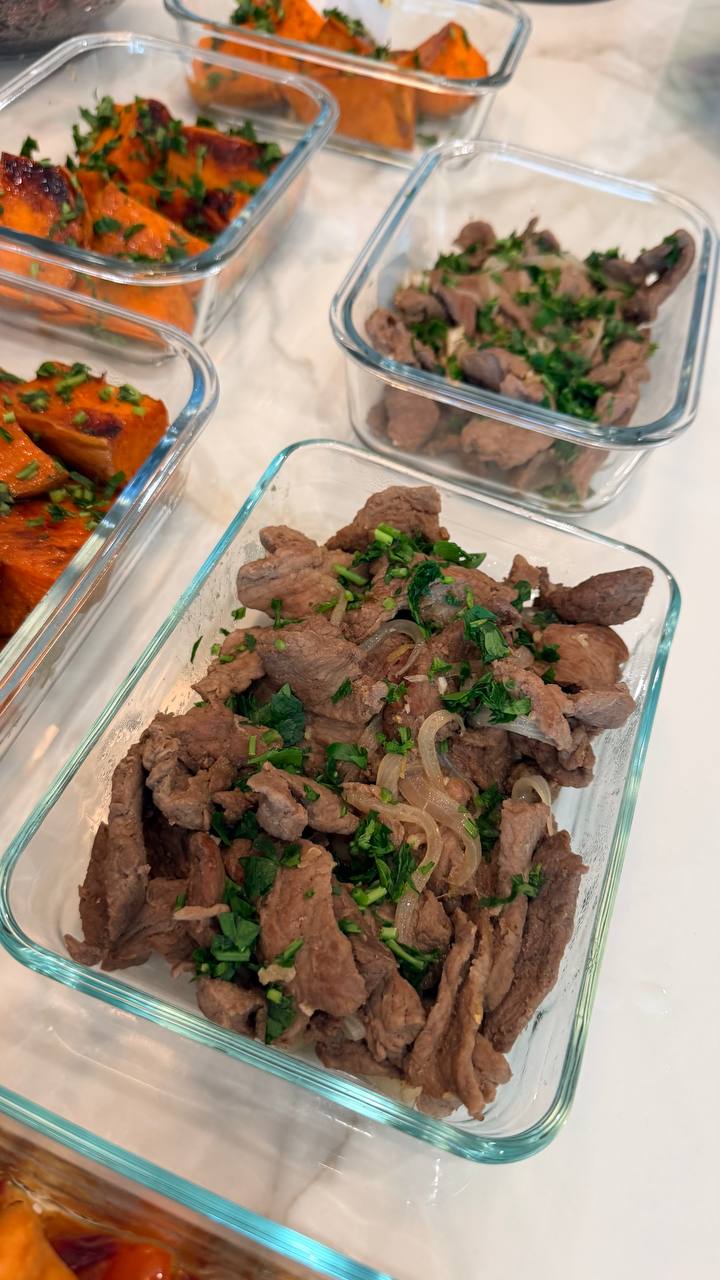 Glass meal prep containers filled with savory beef bulgogi with onions and roasted sweet potato halves, all garnished with freshly chopped green herbs.