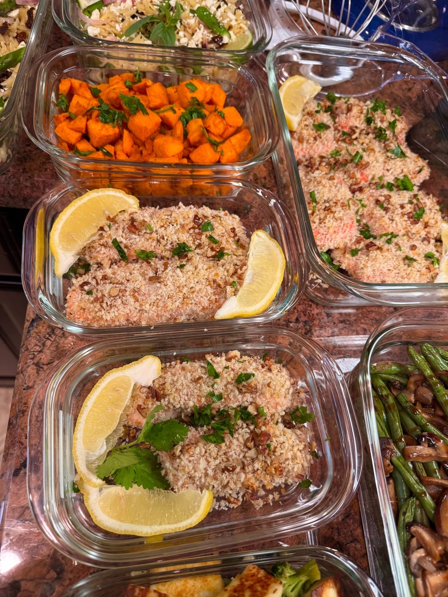 Glass meal prep containers filled with crispy pecan crusted salmon, bright orange paprika sweet potato cubes, and balsamic green beans with sautéed mushrooms.