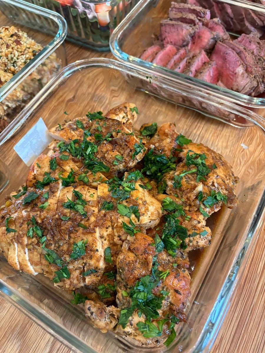 Glass meal prep containers filled with beef sirloin strips with mushrooms, Mediterranean salmon with olives, garlic sweet potatoes, and seared asparagus with pancetta.