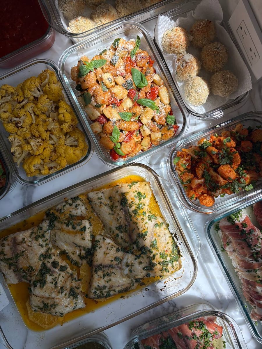 A curated collection of glass meal prep containers featuring protein-rich dishes and fresh Mediterranean sides, highlighting the premium culinary service.