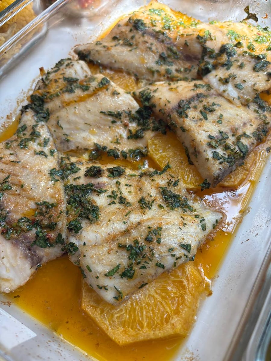 Tender barramundi fillets baked with citrus slices and fragrant herbs, showing the high-quality culinary standards of local private chef services in Houston.