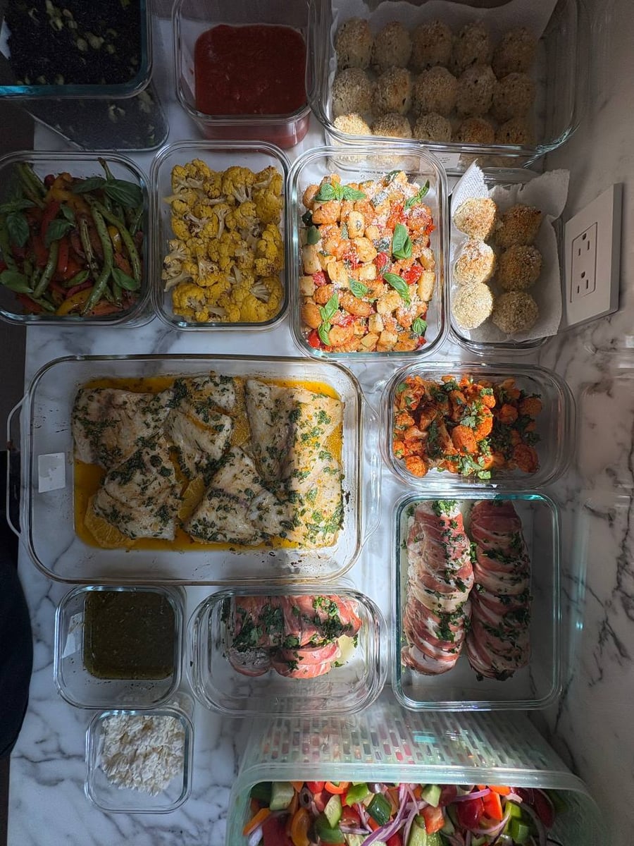 Top-down view of an assortment of gourmet meal prep dishes including stuffed turkey, colorful Greek salads, and roasted cauliflower for Houston families.