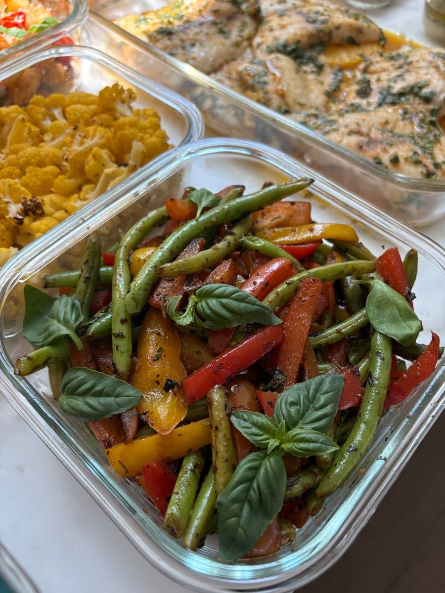 Close up of vibrant roasted green beans and yellow bell peppers with fresh basil, prepared by a private chef in Houston, TX for healthy weekly dining.