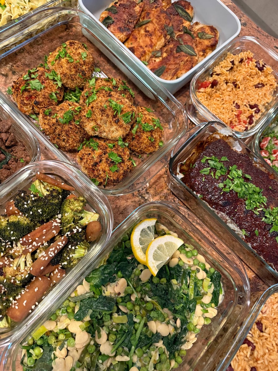 Golden panko shrimp cakes scattered with parsley, sesame broccoli and carrots crowding in from the left.