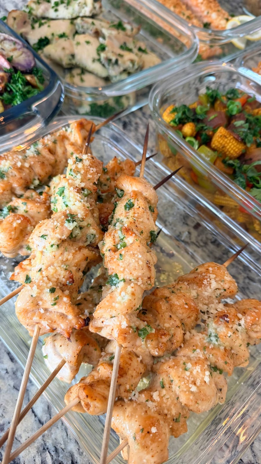 Grated parmesan clings to parsley on five chicken skewers, baby corn stir fry to the right.