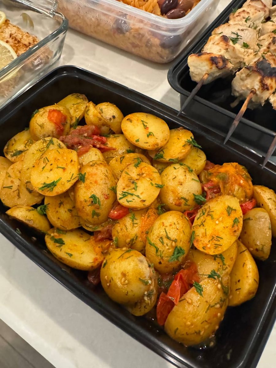 Dill and burst cherry tomatoes cling to the halved fingerling potatoes, chicken skewers resting above.