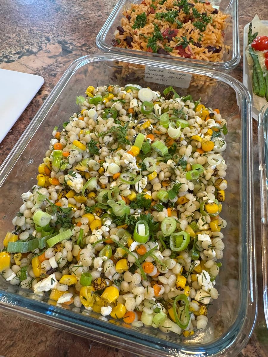 Pearled couscous holds charred corn, crumbled feta, scallion rings and chopped herbs beneath the Spanish rice.