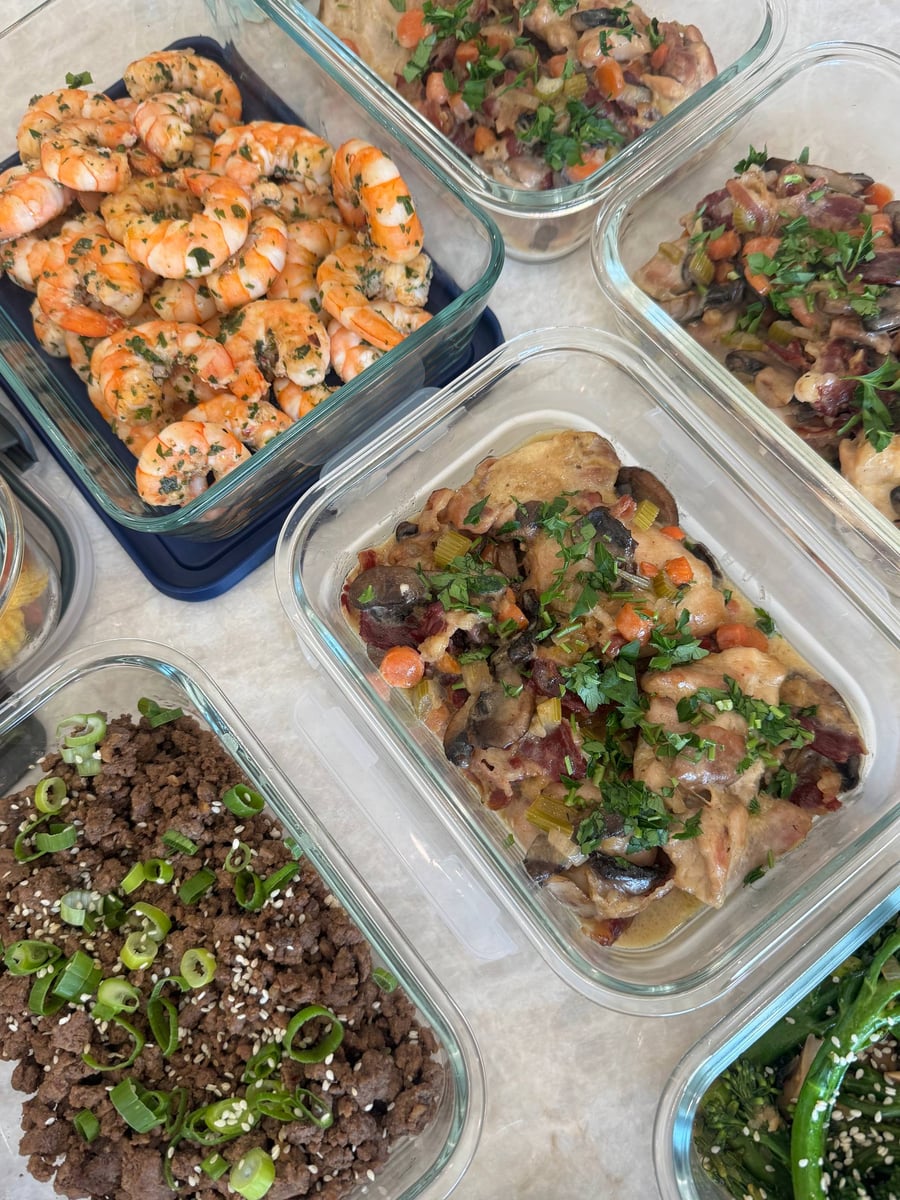 Herb-coated chimuchuri shrimp curl beside coq au vin chicken covered with mushrooms, carrots, bacon and parsley.