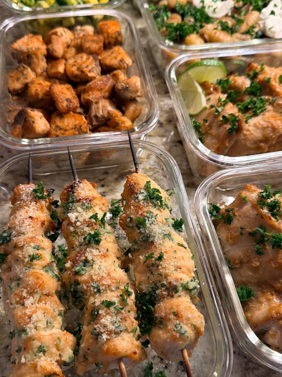 Grated parmesan and parsley cling to three chicken skewers, cashew lime thighs waiting behind them.
