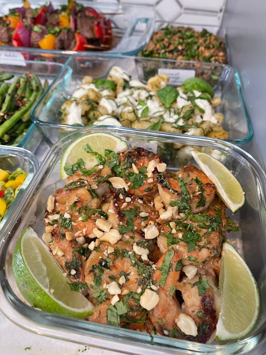 Chopped cashews and shredded basil cover the shrimp, lime wedges pushed into all four corners.
