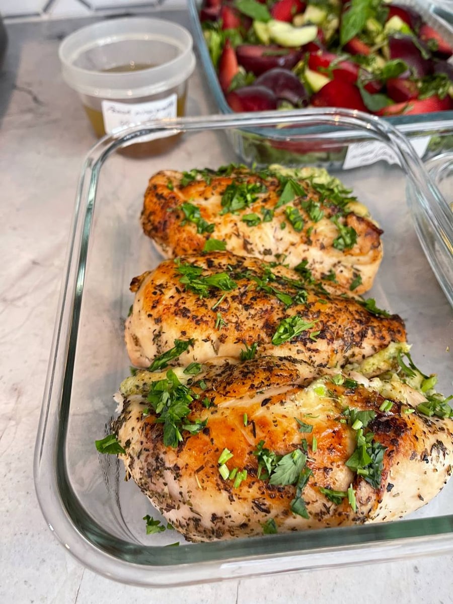 Broccoli and cheese show at the seam of three stuffed breasts, herbs baked dark across the top.
