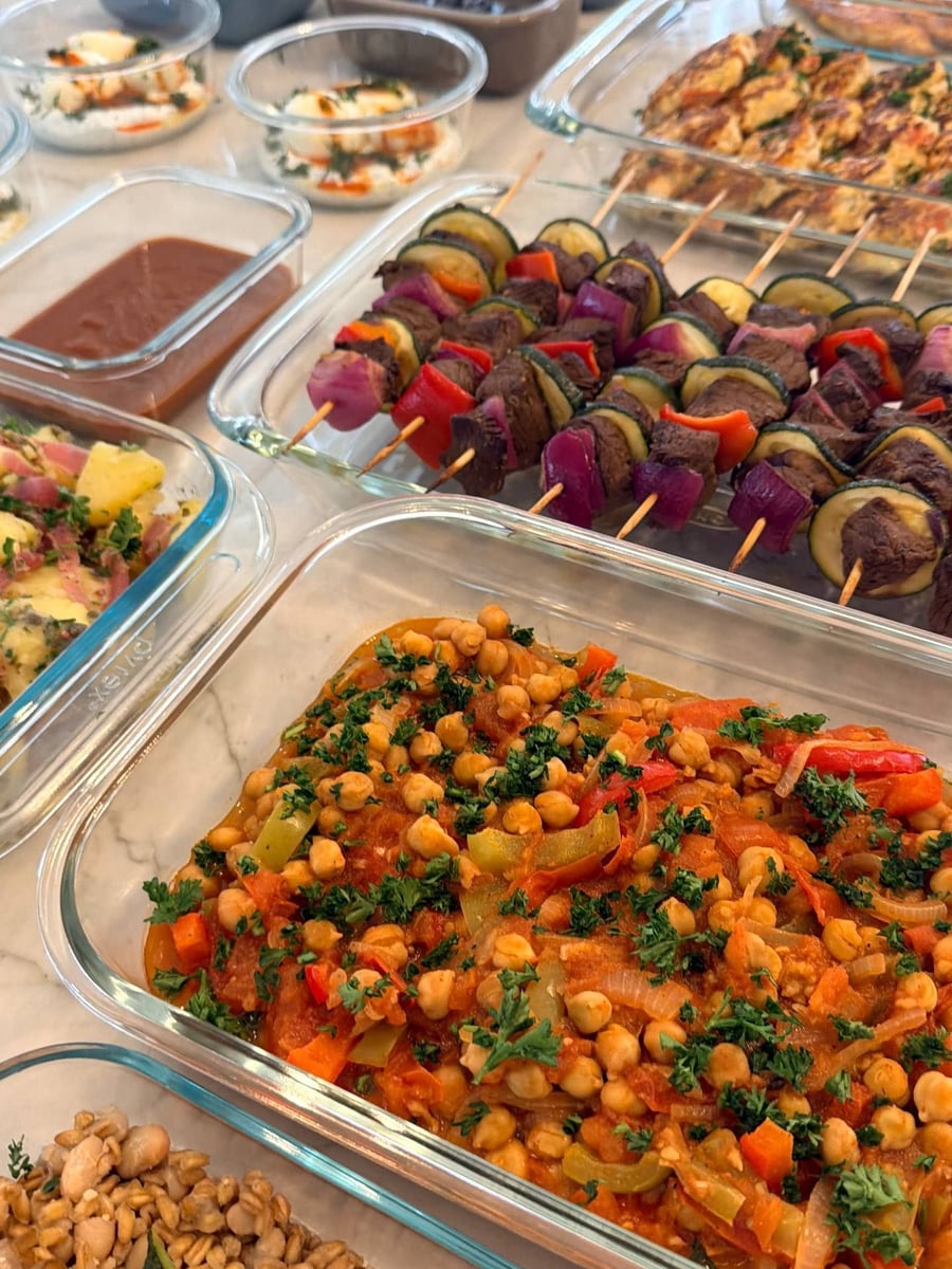 Chickpeas sit in tomato with soft bell pepper strips, parsley thrown across the whole tray.
