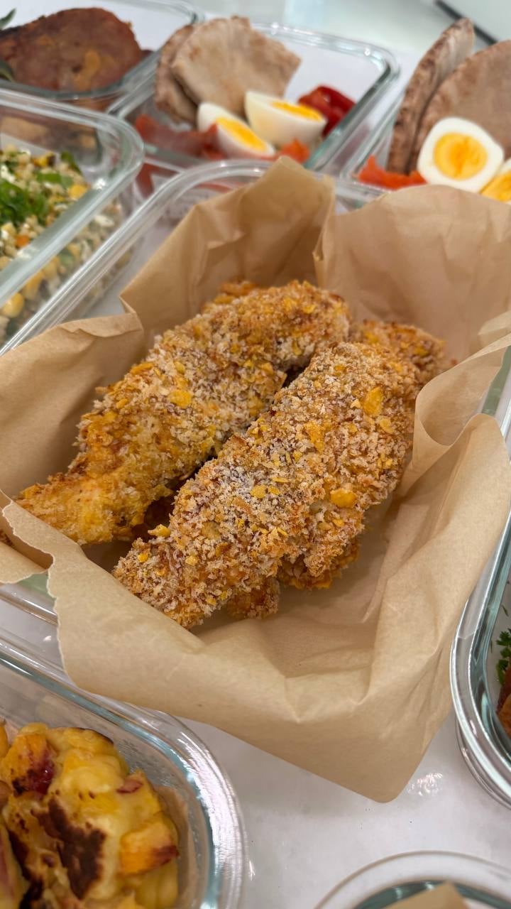 Cornflake and panko crust covers the chicken tenders resting in their parchment lining.