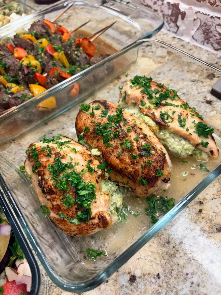 Broccoli and melted cheese spill from seared chicken breast roulades under parsley, with peppered sirloin kebabs behind.