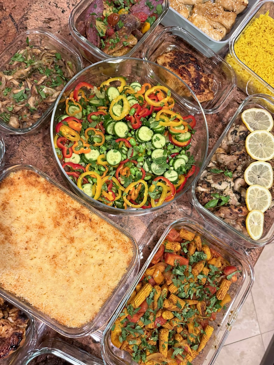 Lemon rounds line basil chicken thighs beside edamame salad, baked macaroni, baby corn stir fry and turmeric rice.
