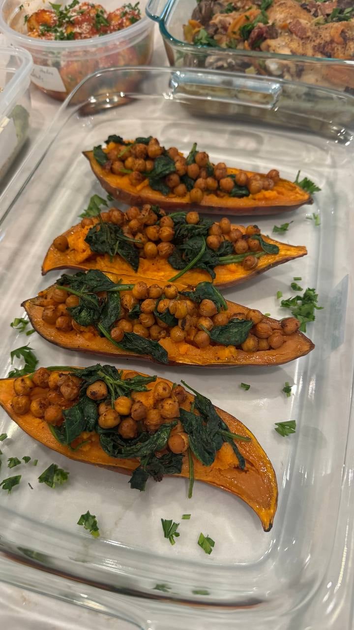 Charred chickpeas and wilted spinach fill four sweet potato halves, parsley flecked across the tray.