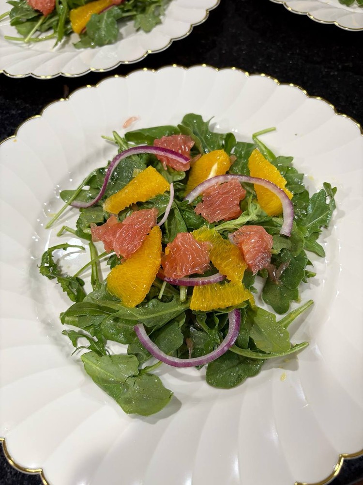 Mixed green salad with grapefruit, oranges, and red onion.