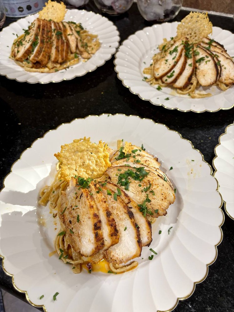 Cajun chicken Alfredo pasta with sliced chicken and parmesan crisp.
