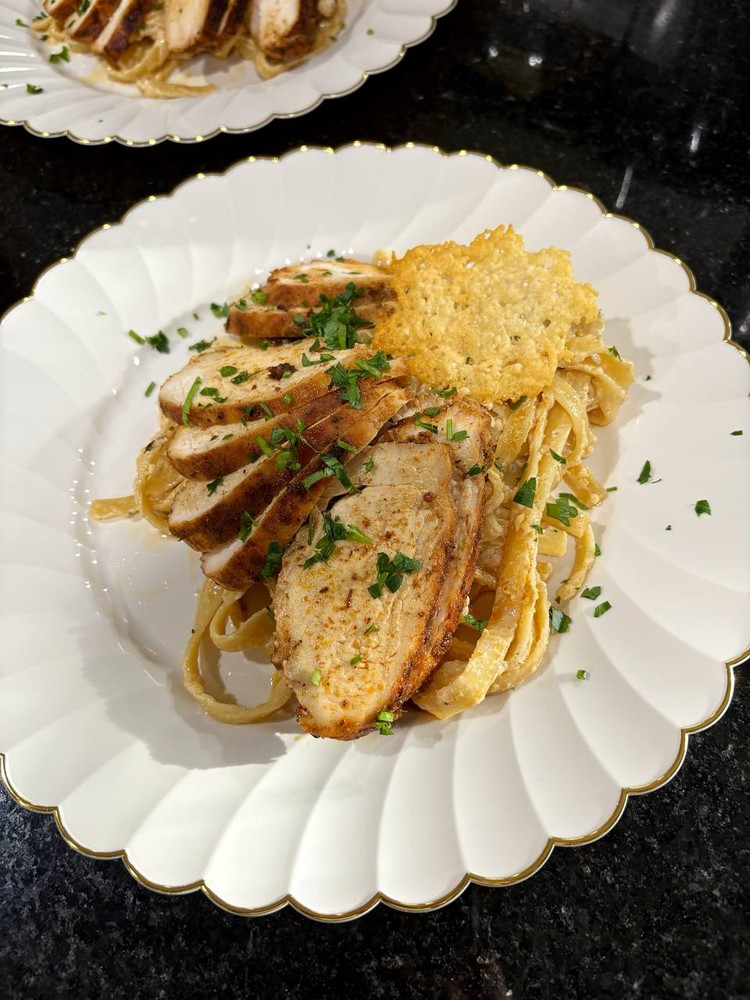 Cajun chicken Alfredo pasta with sliced chicken and fresh parsley.