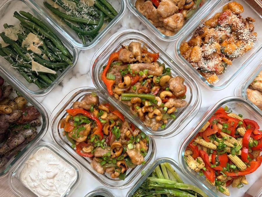 Cashew chicken and meatballs sit among green beans, potatoes, broccolini, skewers and edamame salad with orange segments.