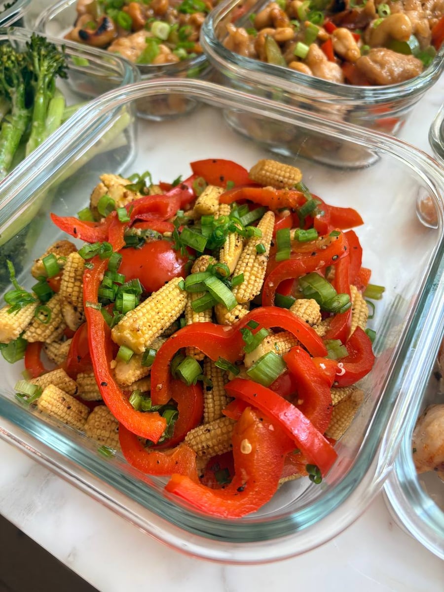 Tomato basil sauce coats Italian meatballs under a thick layer of ribboned fresh basil in a rectangular baker.