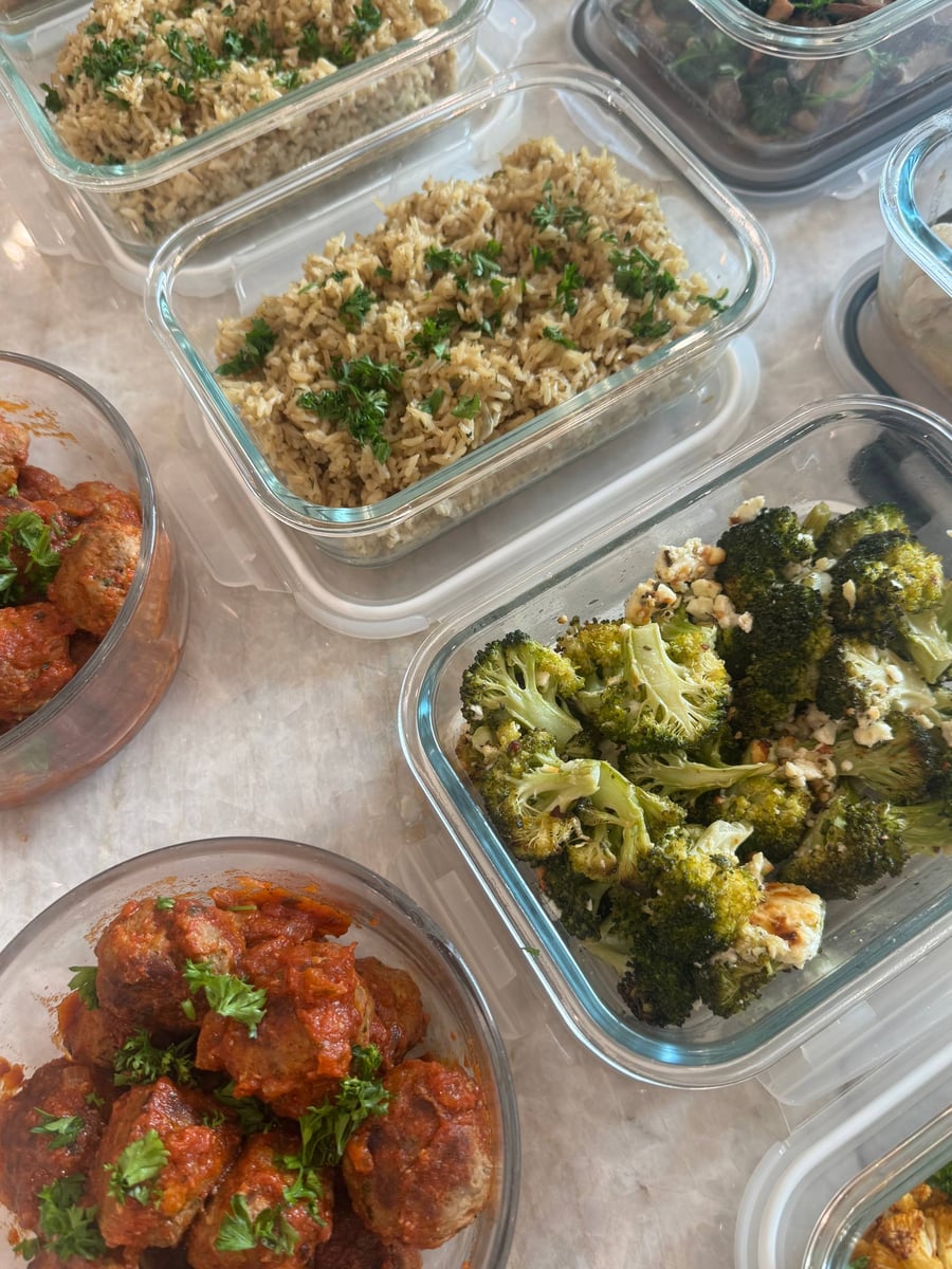 Parsley-topped Italian meatballs sit in tomato basil sauce beside feta broccoli and two pans of lemony brown rice.