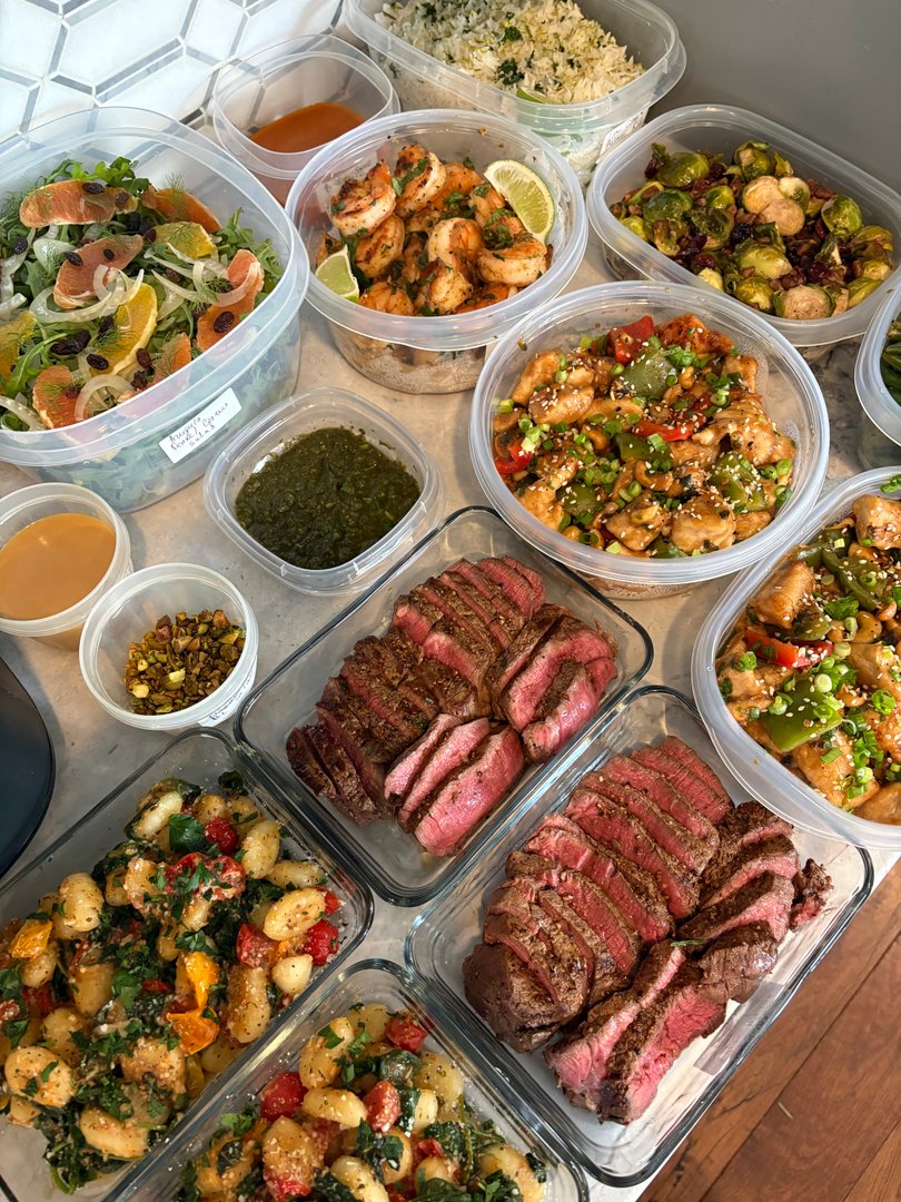 Assorted gourmet meal prep containers with rosemary filet and vibrant sides.