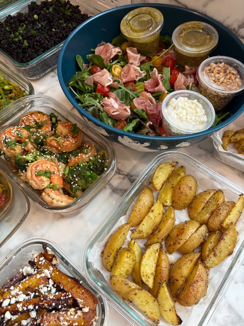 Assorted meal prep containers featuring salad, shrimp, potatoes, and black rice.
