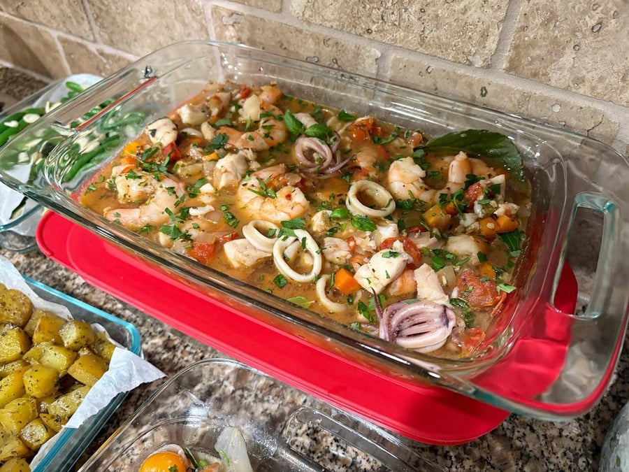 Seafood medley with shrimp, calamari, and vegetables in glass baking dish.