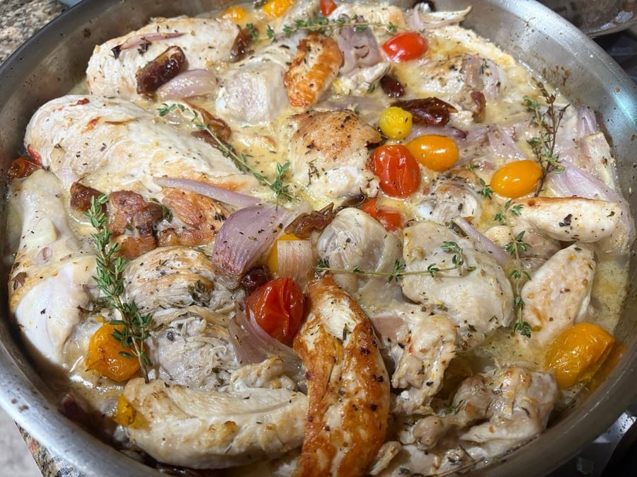 Close-up of roasted chicken thighs with cherry tomatoes and herbs.