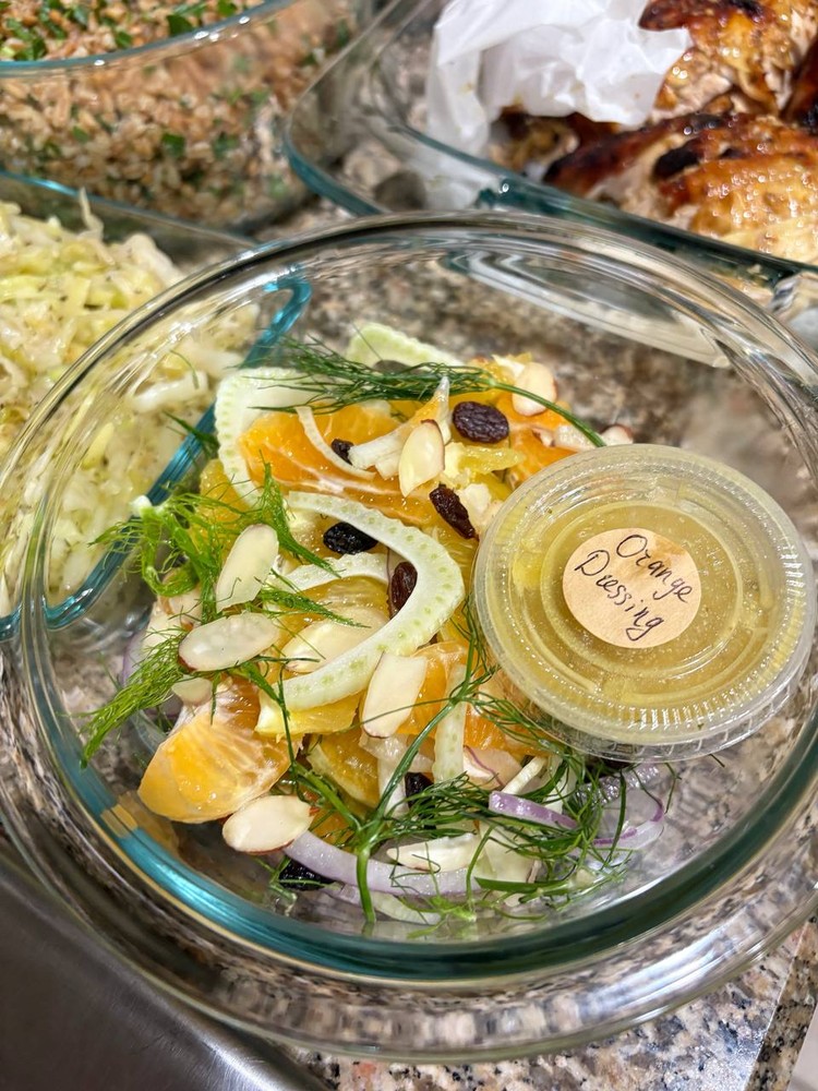 Fennel and orange salad with almonds, raisins, and a side of dressing.