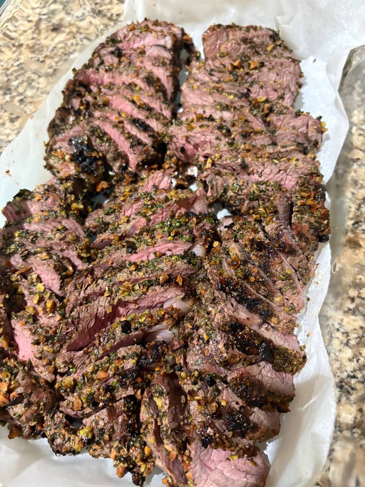 Slices of herb-crusted grilled steak on parchment paper