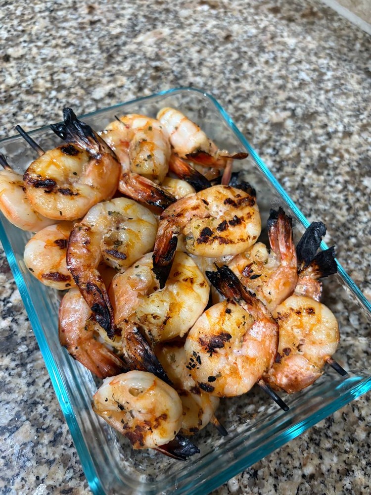 Grilled shrimp skewers in a clear glass container